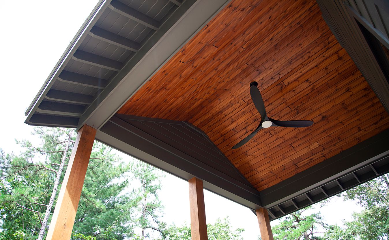 Rustic wooden ceiling with exposed dark beams and natural wood planks in a modern architectural design.