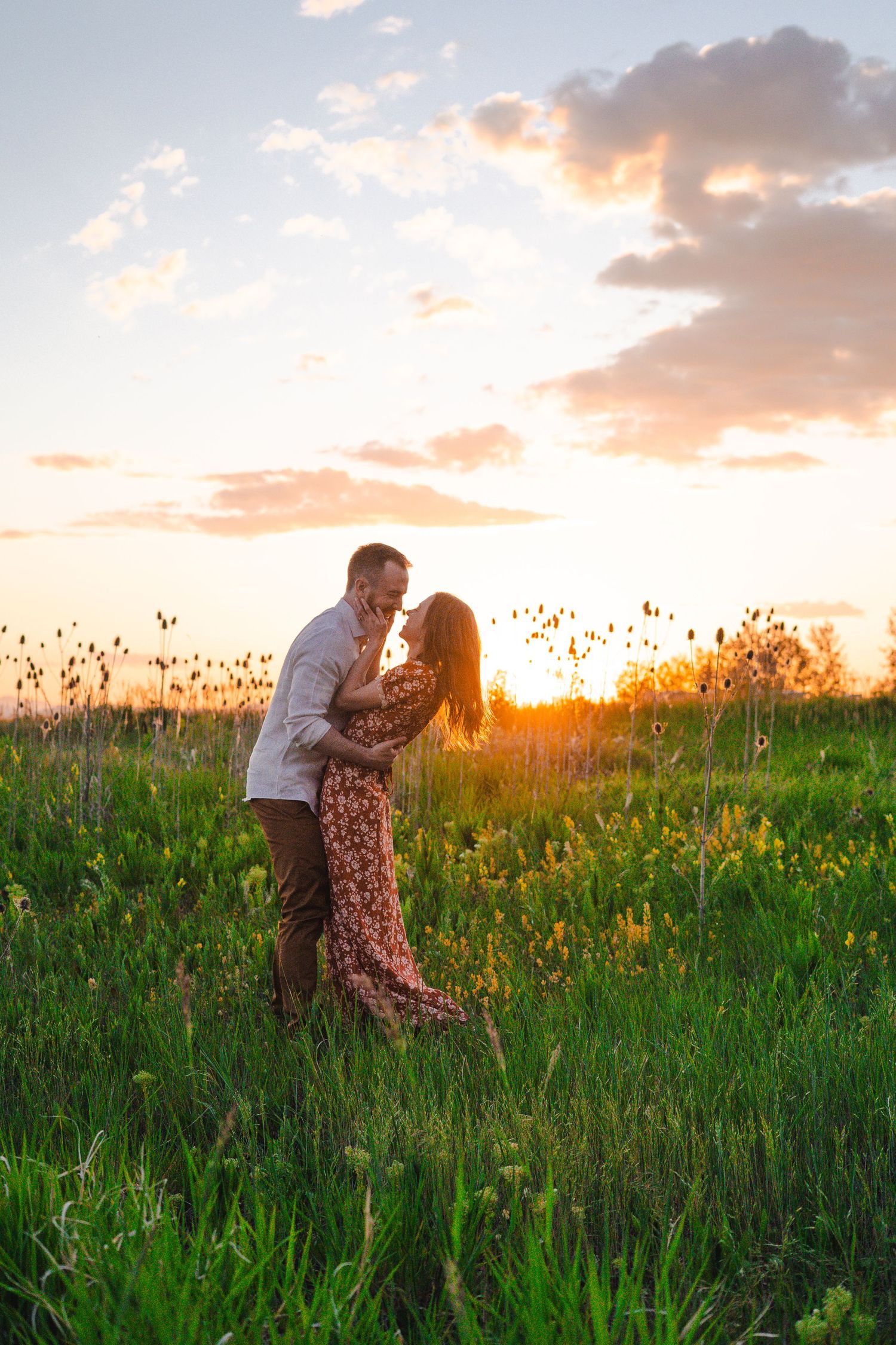 Two people dance together in a meadow at sunset with towering mountains and a lake in the background.