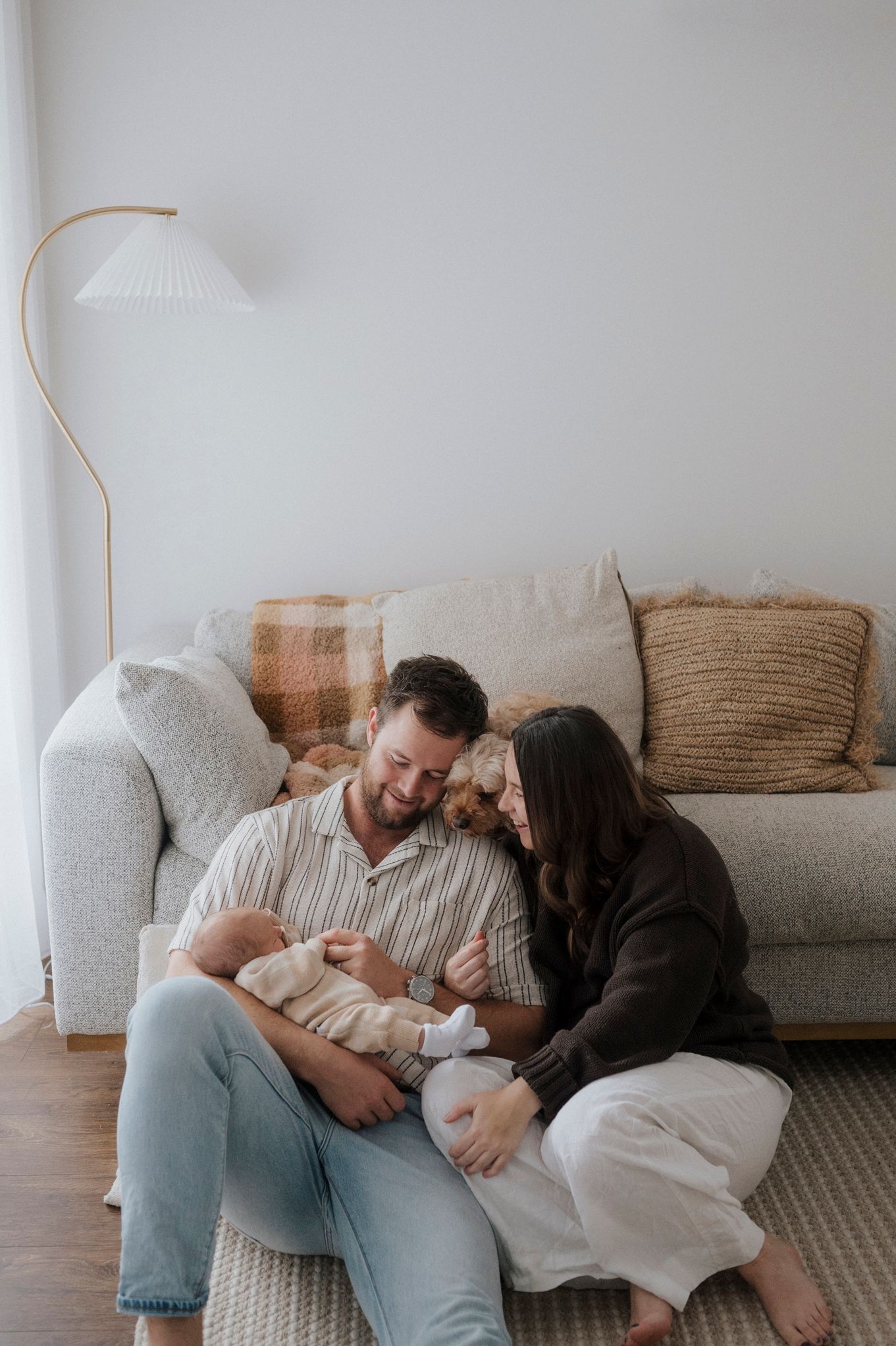 People relaxing together on a comfortable gray couch in a bright, minimalist living room setting.