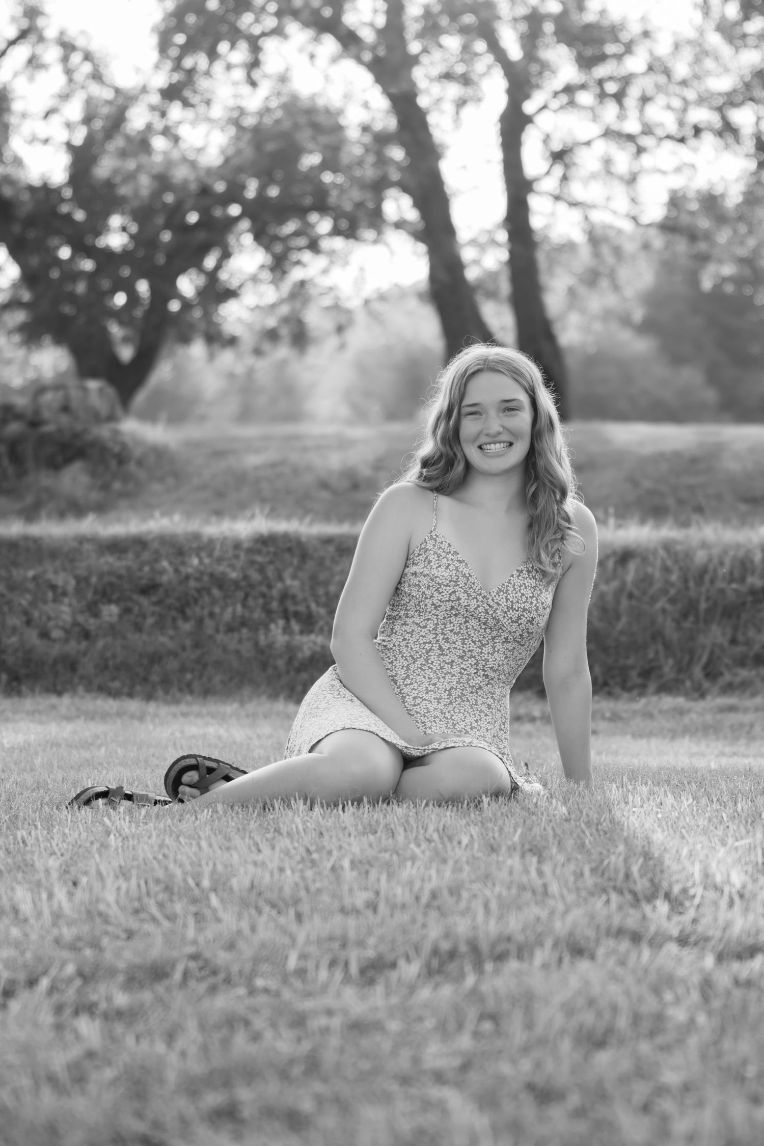 Black and white portrait on grass showing joyful expression in an outdoor garden setting.