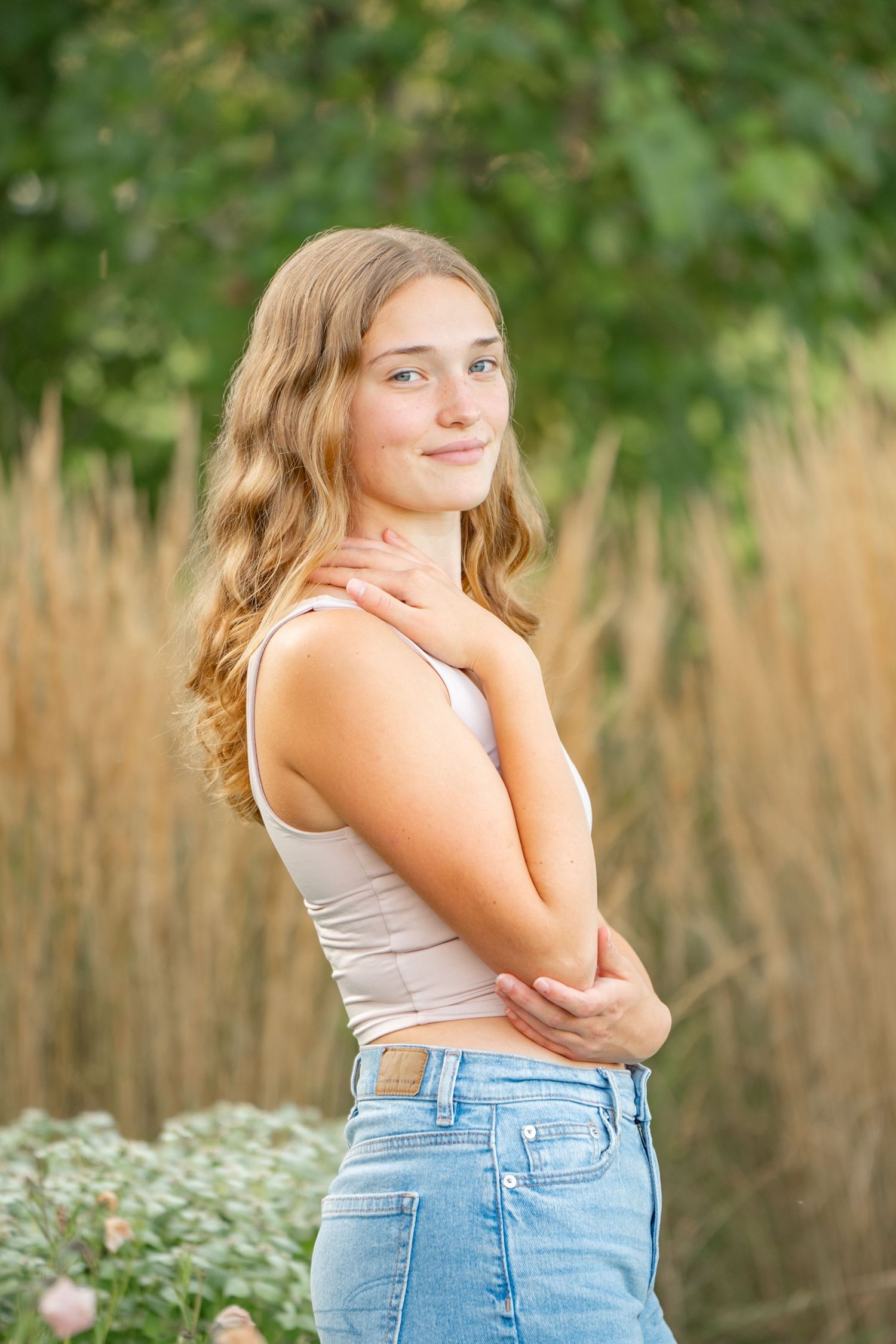 Portrait photo outdoors in natural light with soft bokeh background of tall grass and greenery.