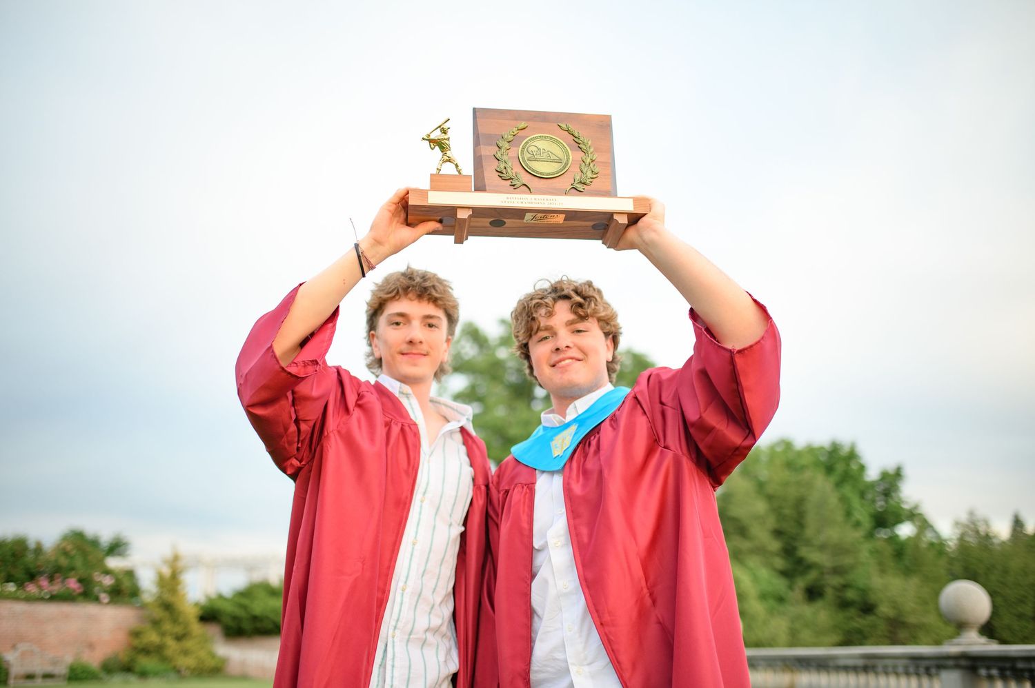 Graduates in red hold up their diplomas excitedly during commencement.