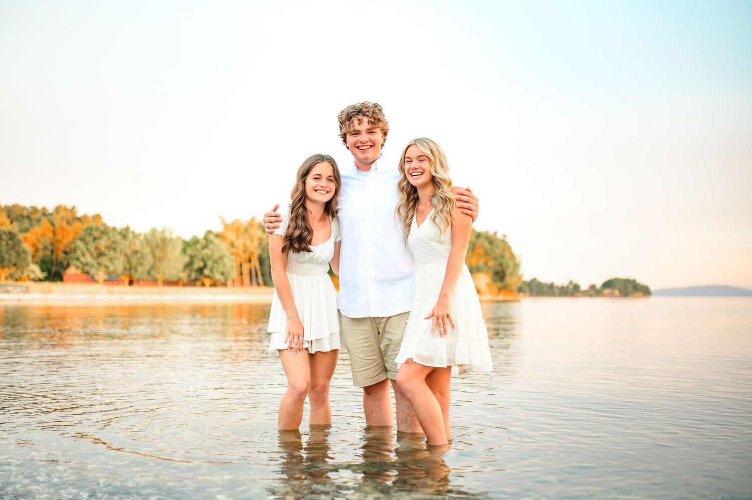 A sunset photo shoot at the lake with people standing in the shallow water.
