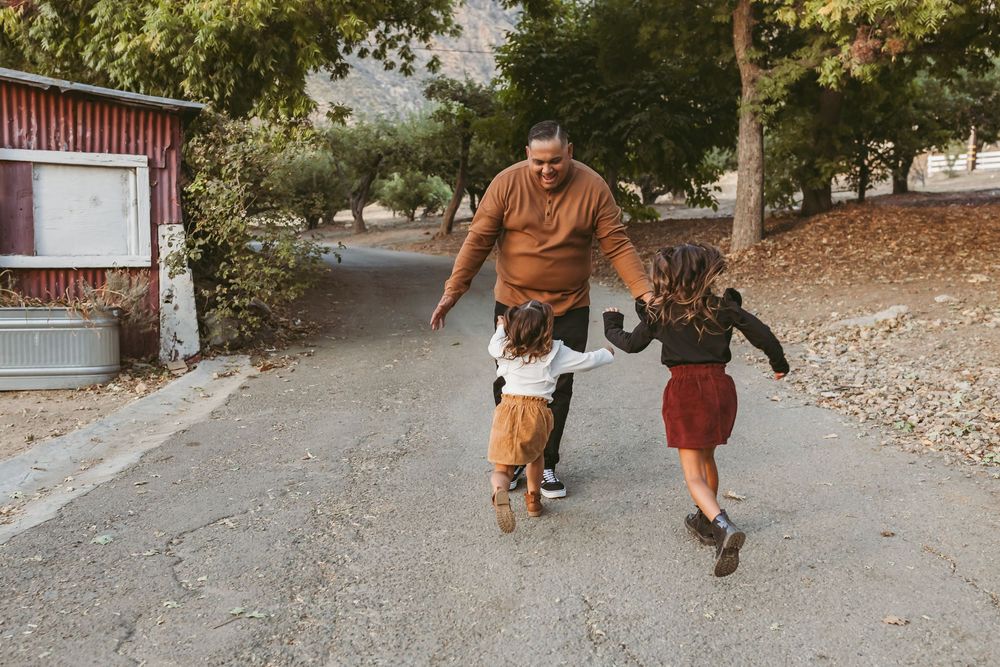 People walking and playing together on a tree-lined pathway during a fall afternoon.