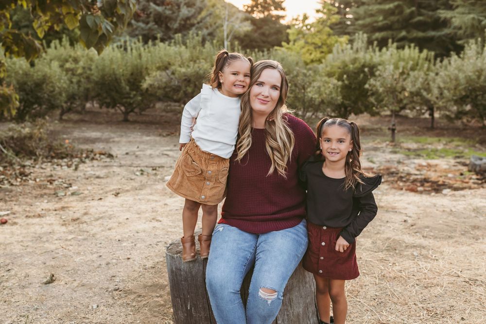 A family poses together outdoors in coordinating burgundy and denim outfits during a fall photography session.
