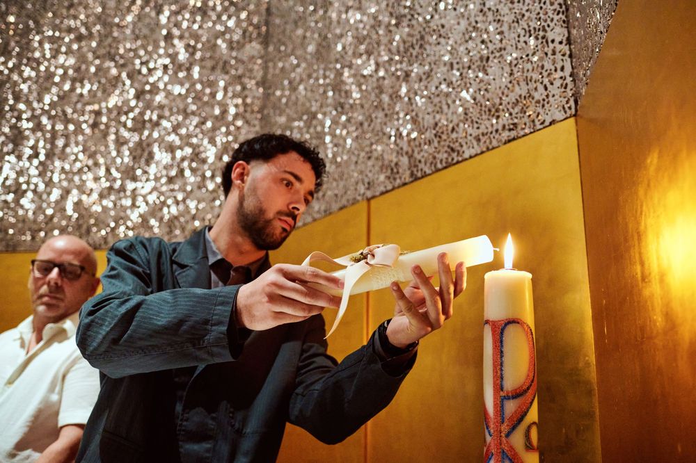 Man lighting ceremonial candle at golden altar during baptism religious ceremony.