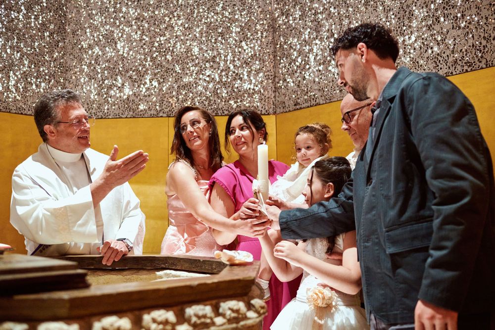 Priest blessing family with candle during baptism ceremony in church.