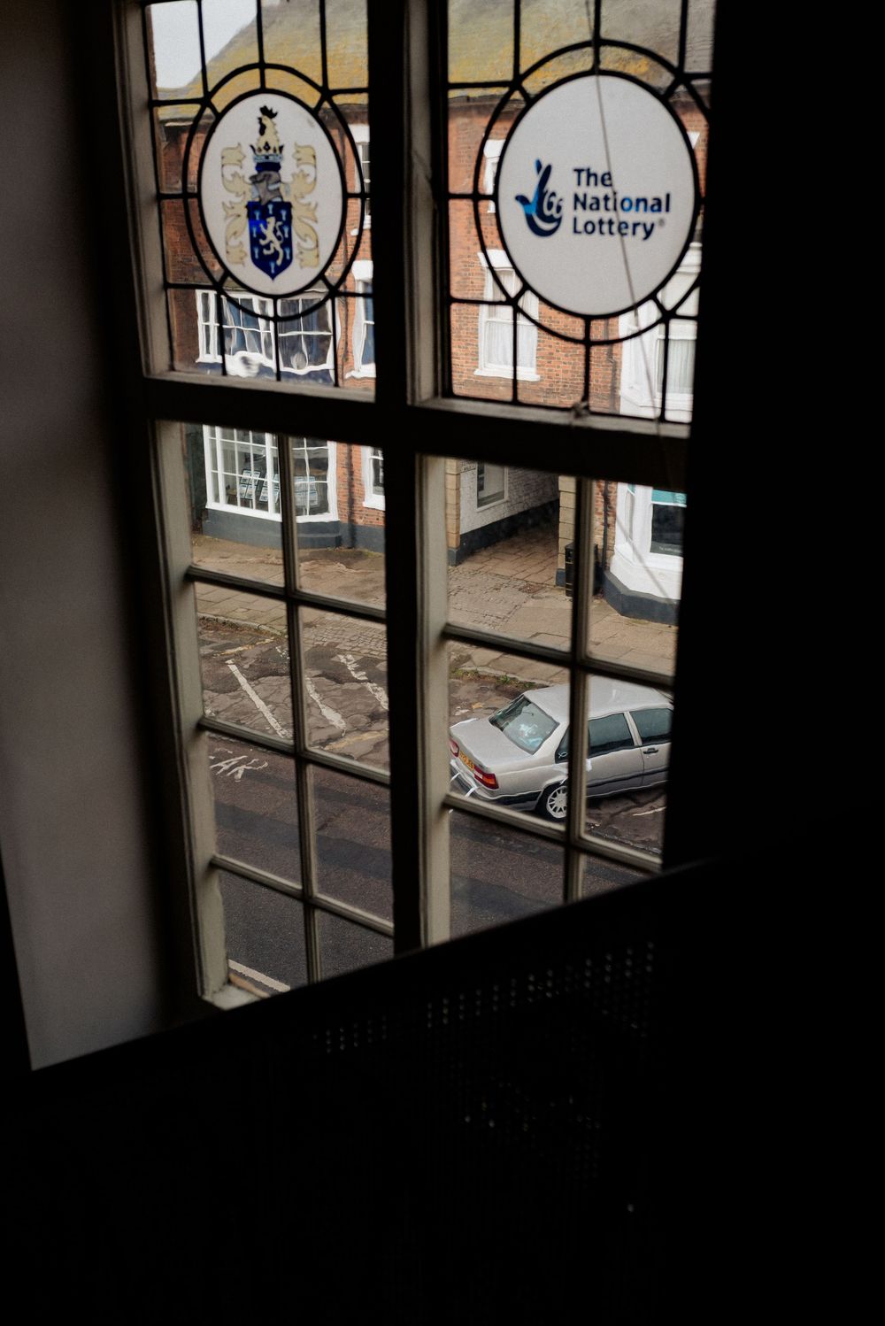 Stained glass window featuring National Lottery and coat of arms logos.