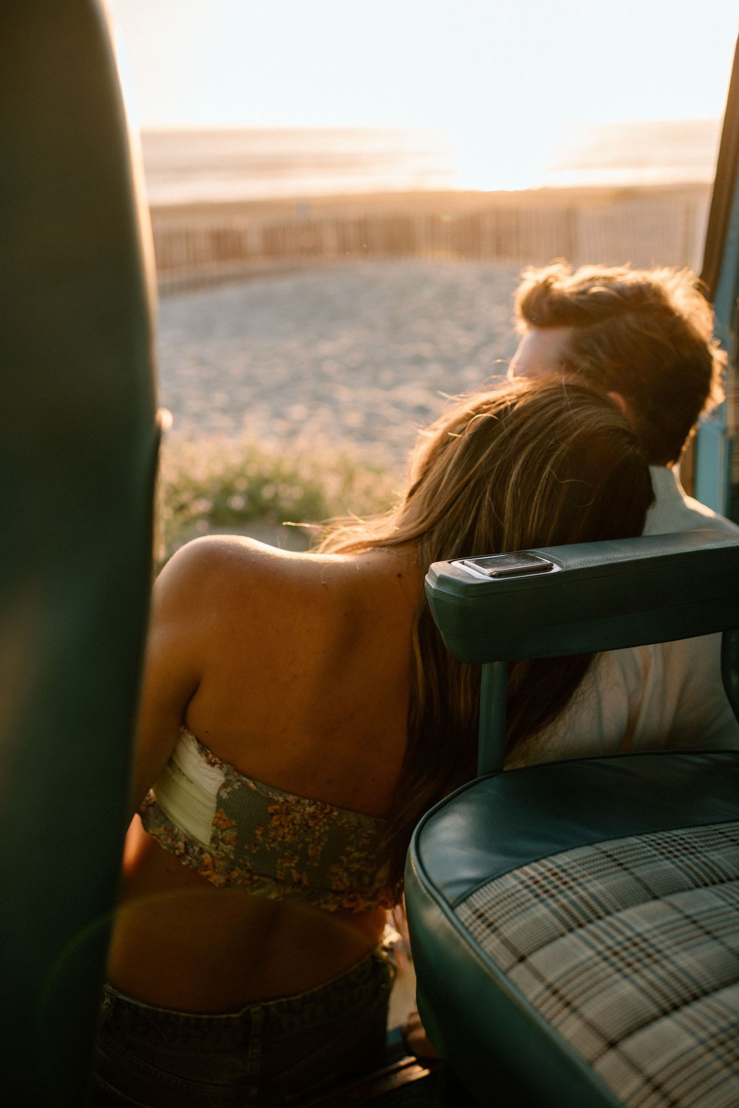 A romantic sunset moment shared through the car window with sunlight casting a warm glow.