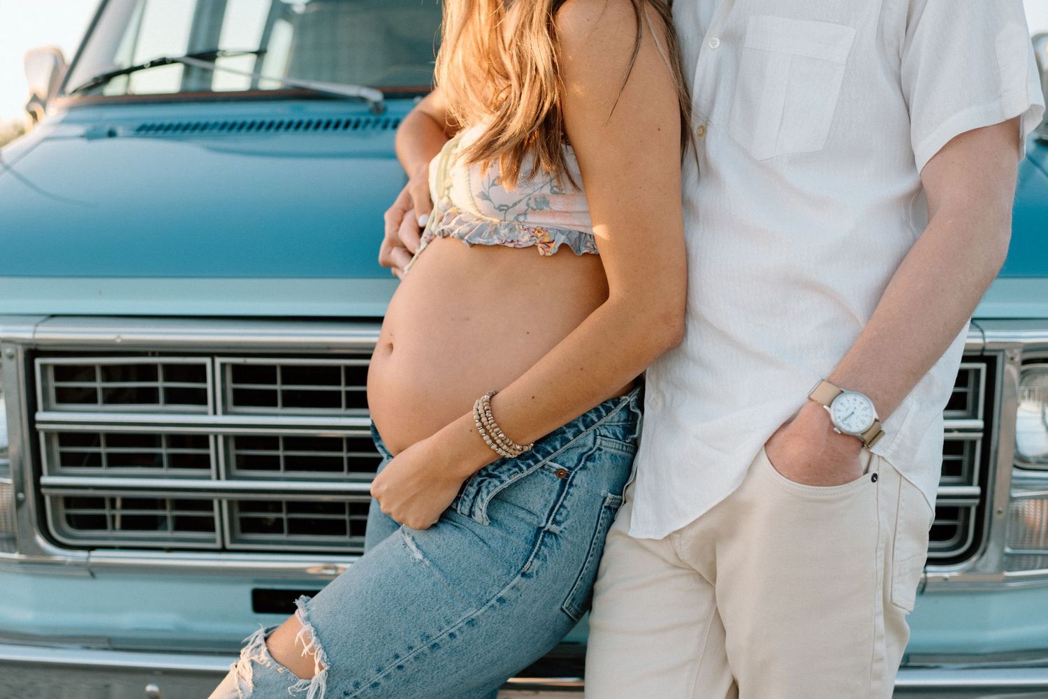 An intimate maternity moment showing a couple posing together against a turquoise pickup truck.