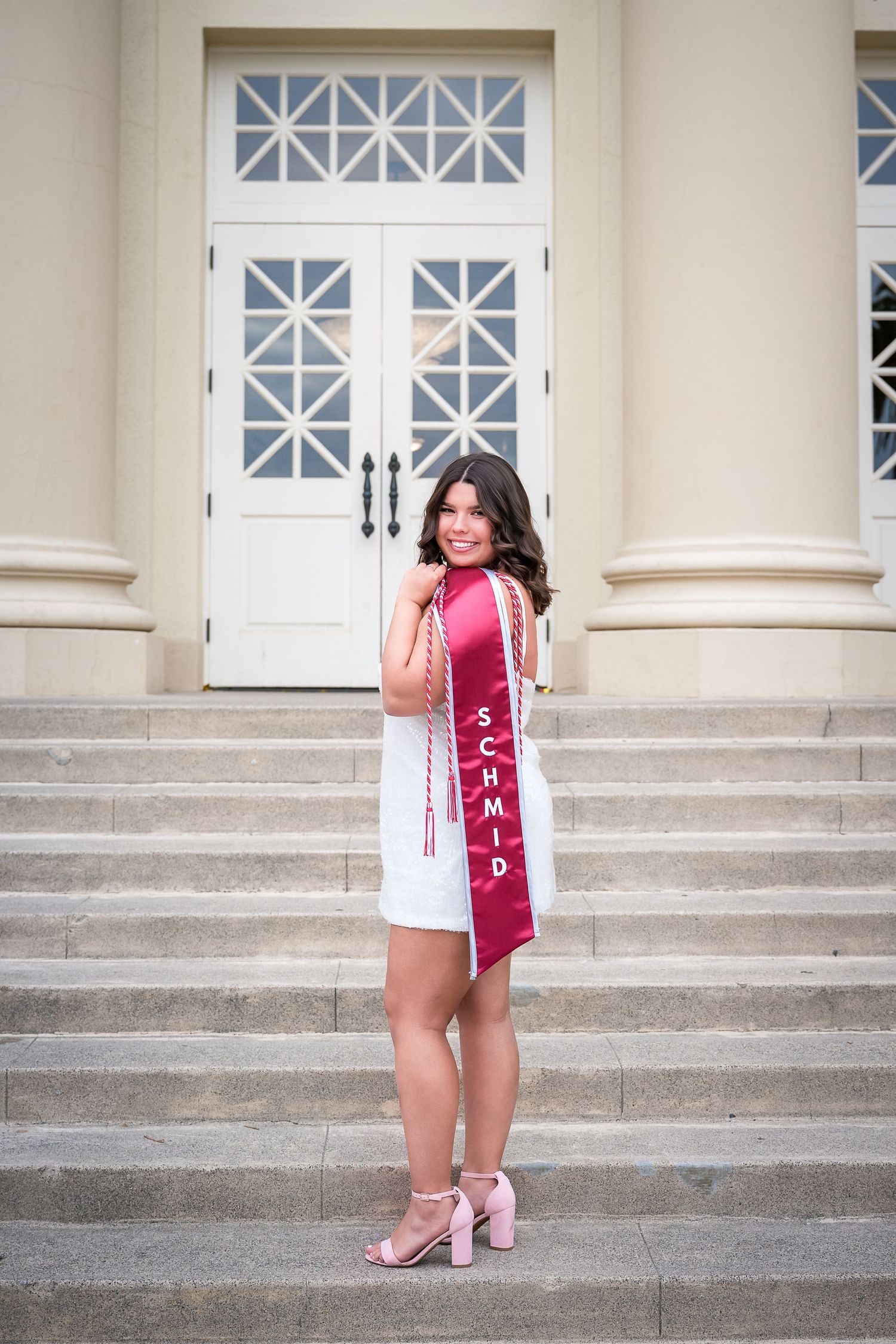 Twin graduates standing side by side in front of Memorial Hall at Chapman University