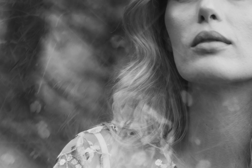 Artistic black and white close-up portrait showing lips and wavy hair with dreamy bokeh effect in background.