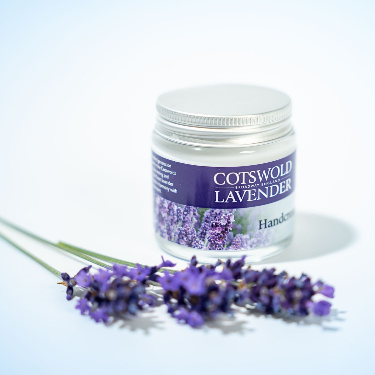 Purple lavender flowers and spa products arranged with white jars and containers for aromatherapy skincare treatments.