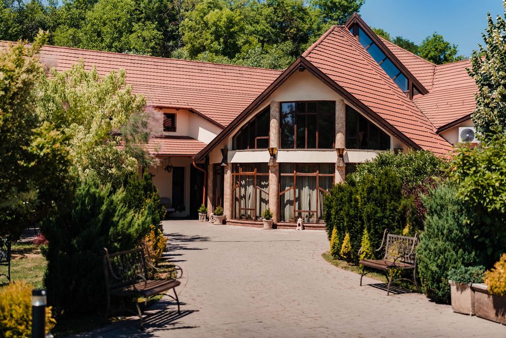 Panoramic view of a rustic wedding venue with red roof and landscaped grounds.