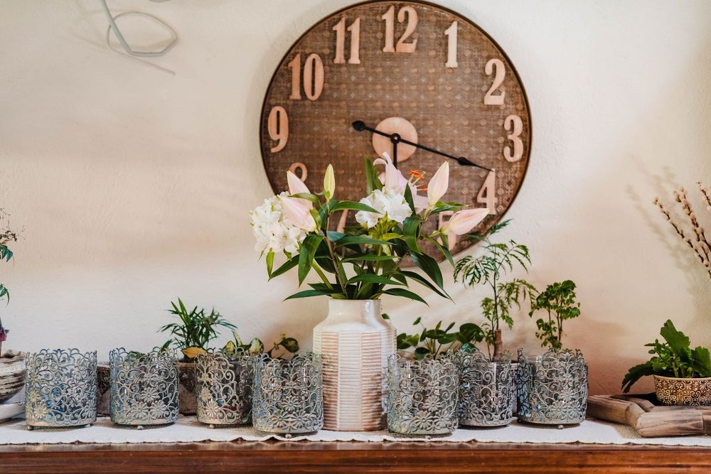 Vintage wall clocks and delicate floral decorations arranged on white shelving.