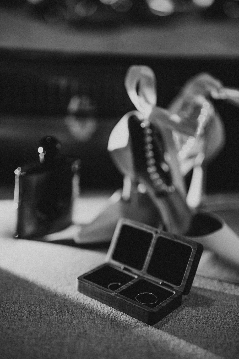 Black and white close-up of wedding ring boxes on textured fabric.