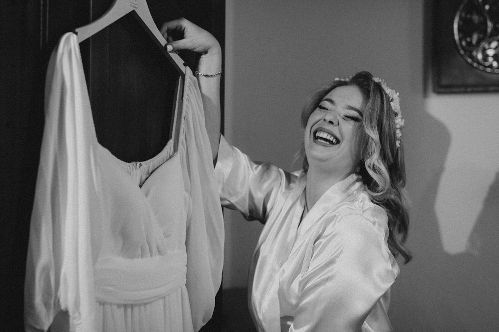 Black and white photo showing joyful laughter while admiring a wedding dress.