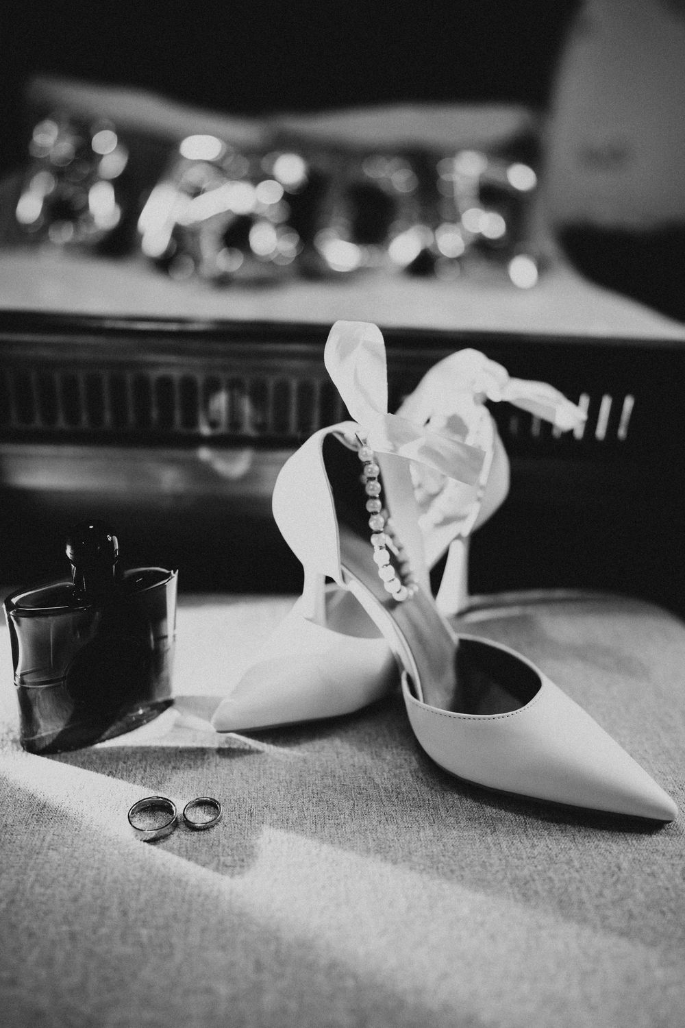 Black and white detail shot of wedding shoes and accessories arranged on fabric.