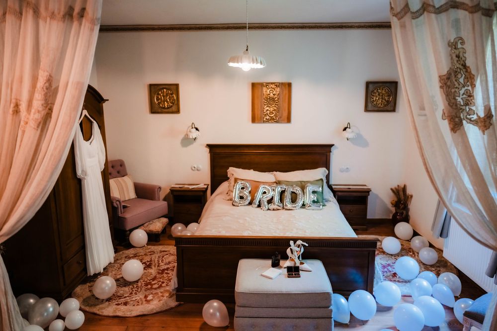 A bedroom decorated with white balloons and pink curtains for wedding preparations.