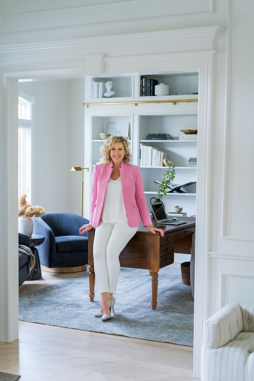 Bright interior photoshoot featuring pink blazer and white pants combination.