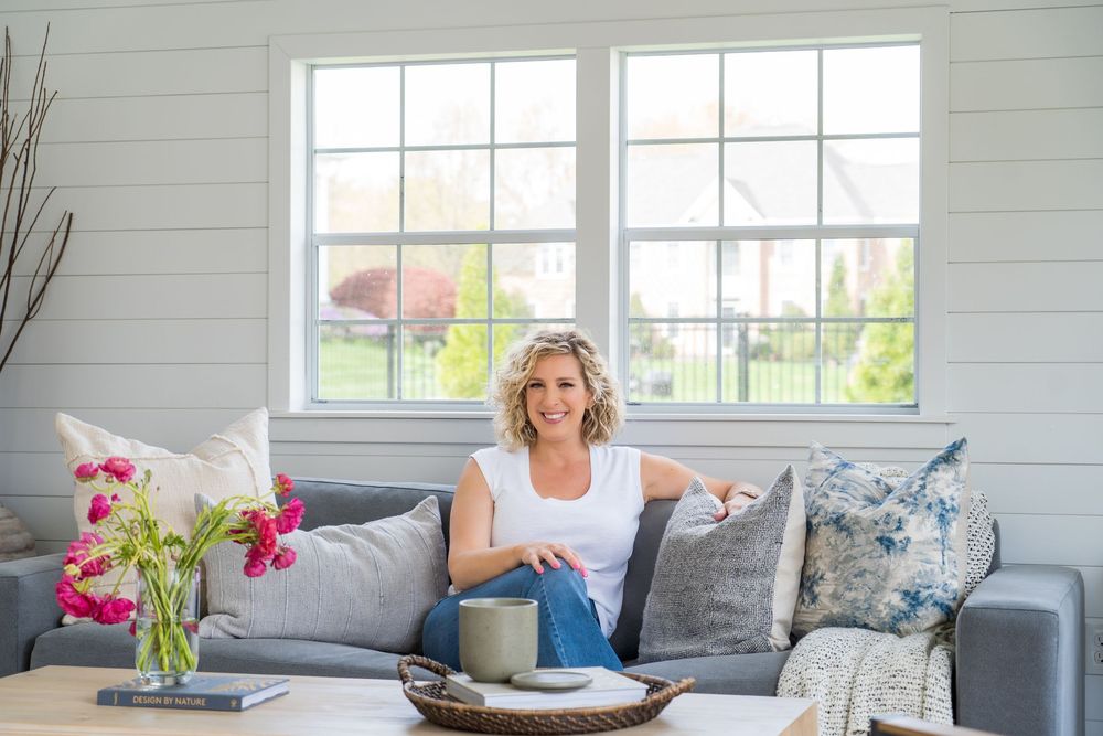 Contemporary living room featuring a gray sofa with decorative pillows and fresh flowers.