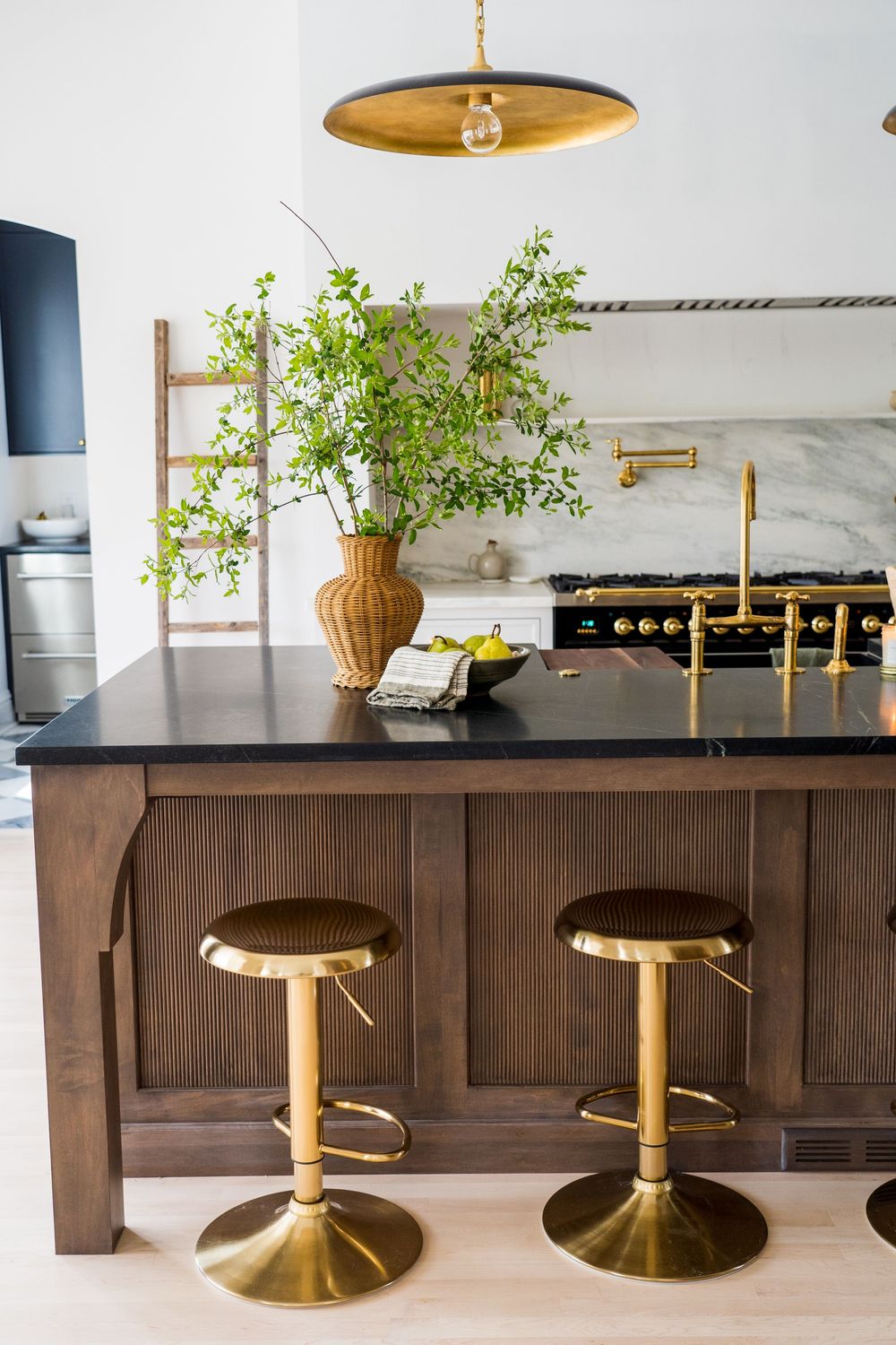 Elegant bar area with brass bar stools and dark wood paneling against white marble countertops.