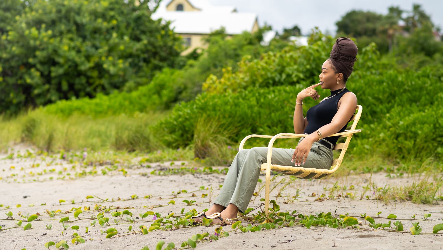 Person sitting alone in chair against lush green background.