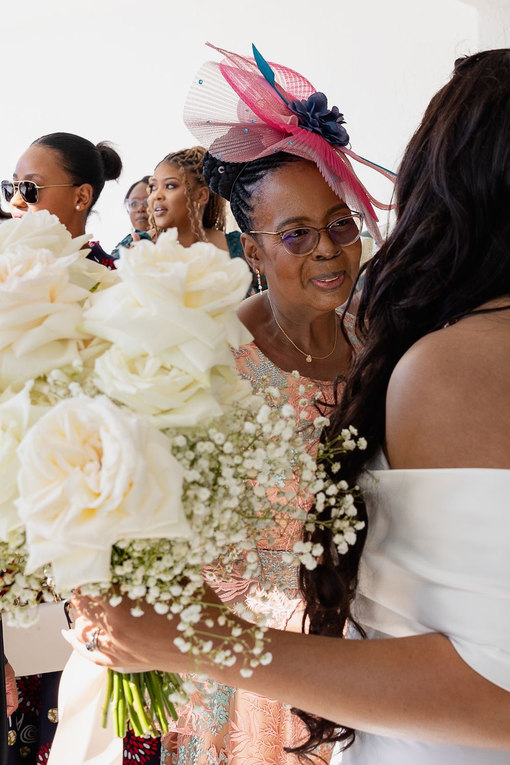 Guests gather at a wedding celebration with elegant floral bouquets featuring white roses and baby's breath.