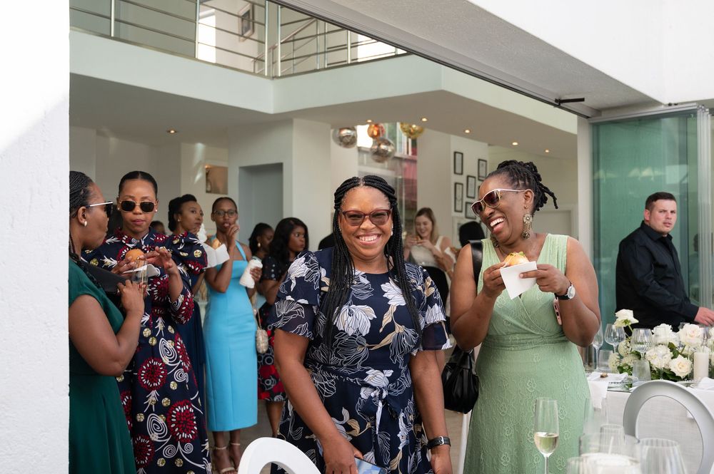 People gather in a bright, modern hallway for a social event in professional attire.