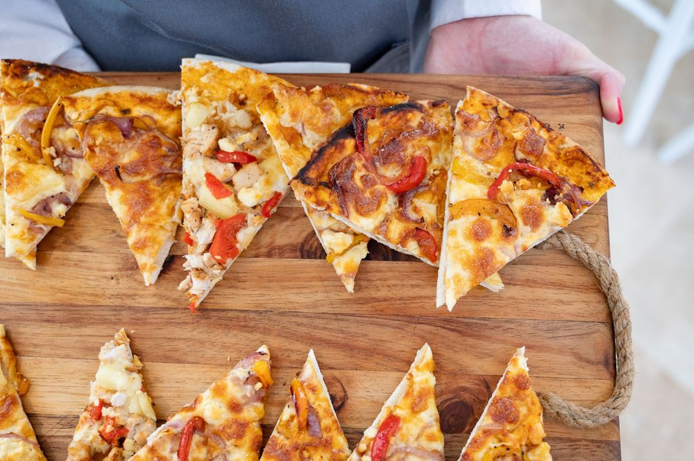 Sliced triangle pieces of homemade BBQ chicken pizza arranged on a wooden cutting board.