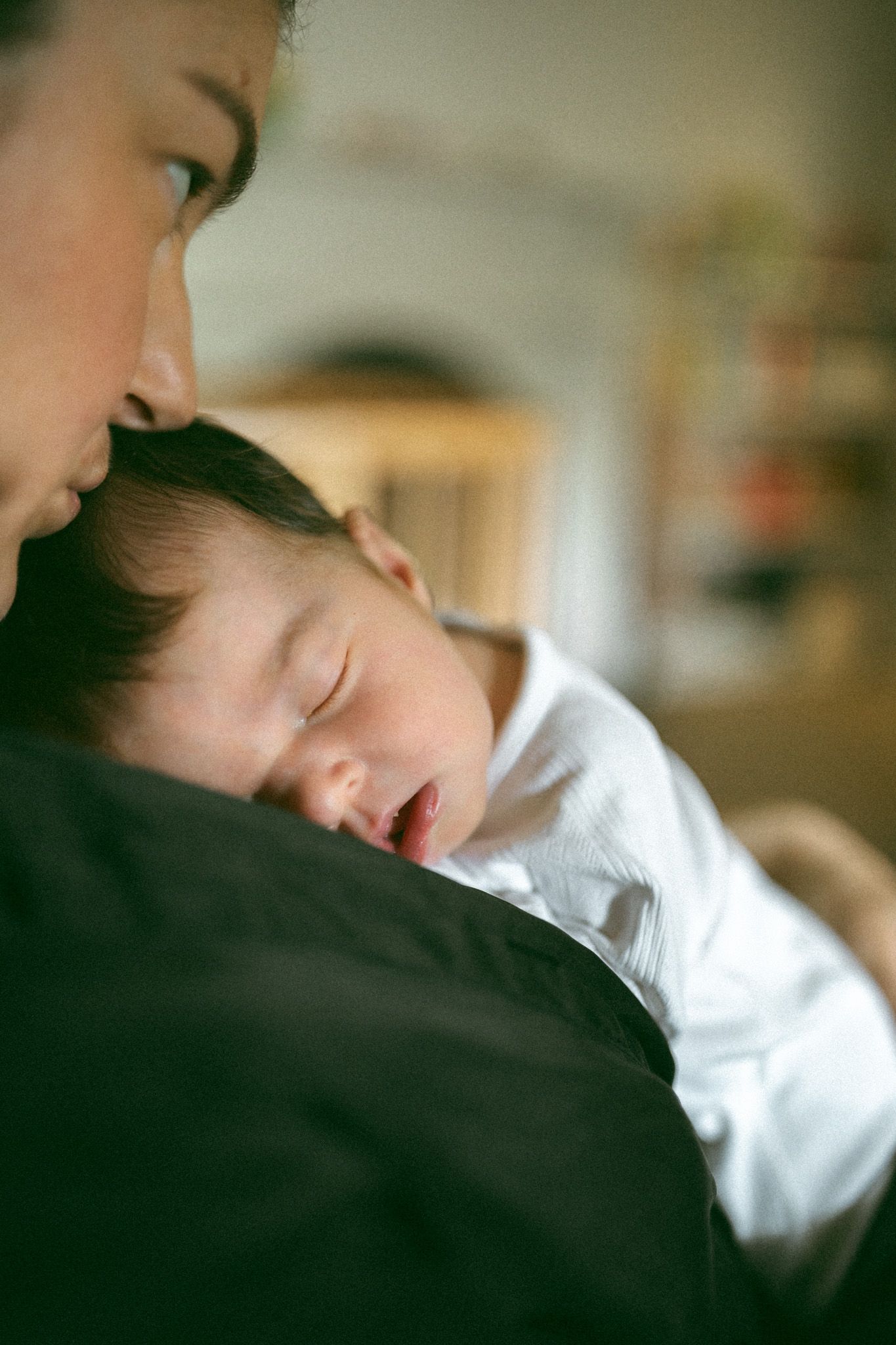 A tender moment as a newborn baby wrapped in a brown knit blanket is gently cradled in loving arms.