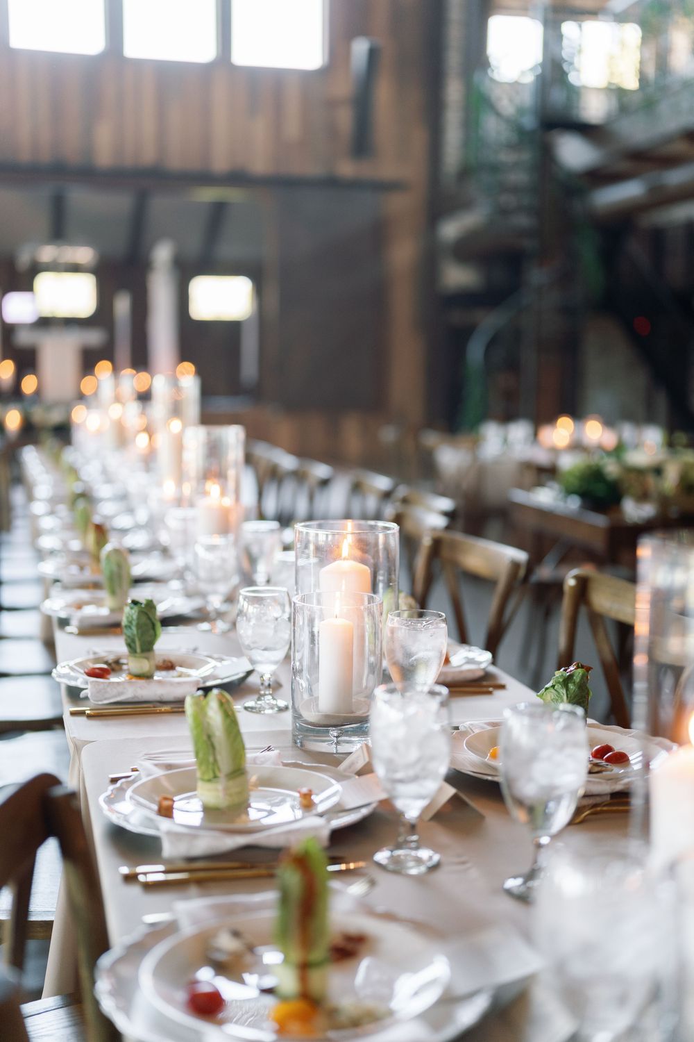 Romantic wedding reception table setting with candles and modern succulent centerpieces.