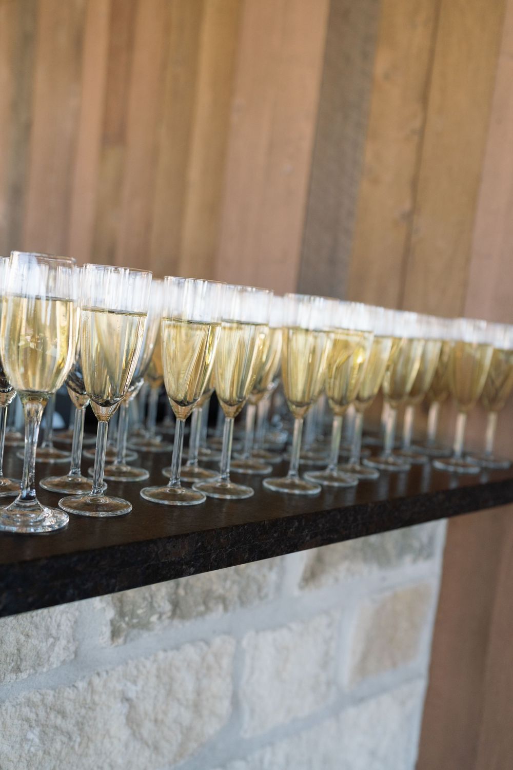 Row of champagne flutes filled with sparkling wine on a dark surface.