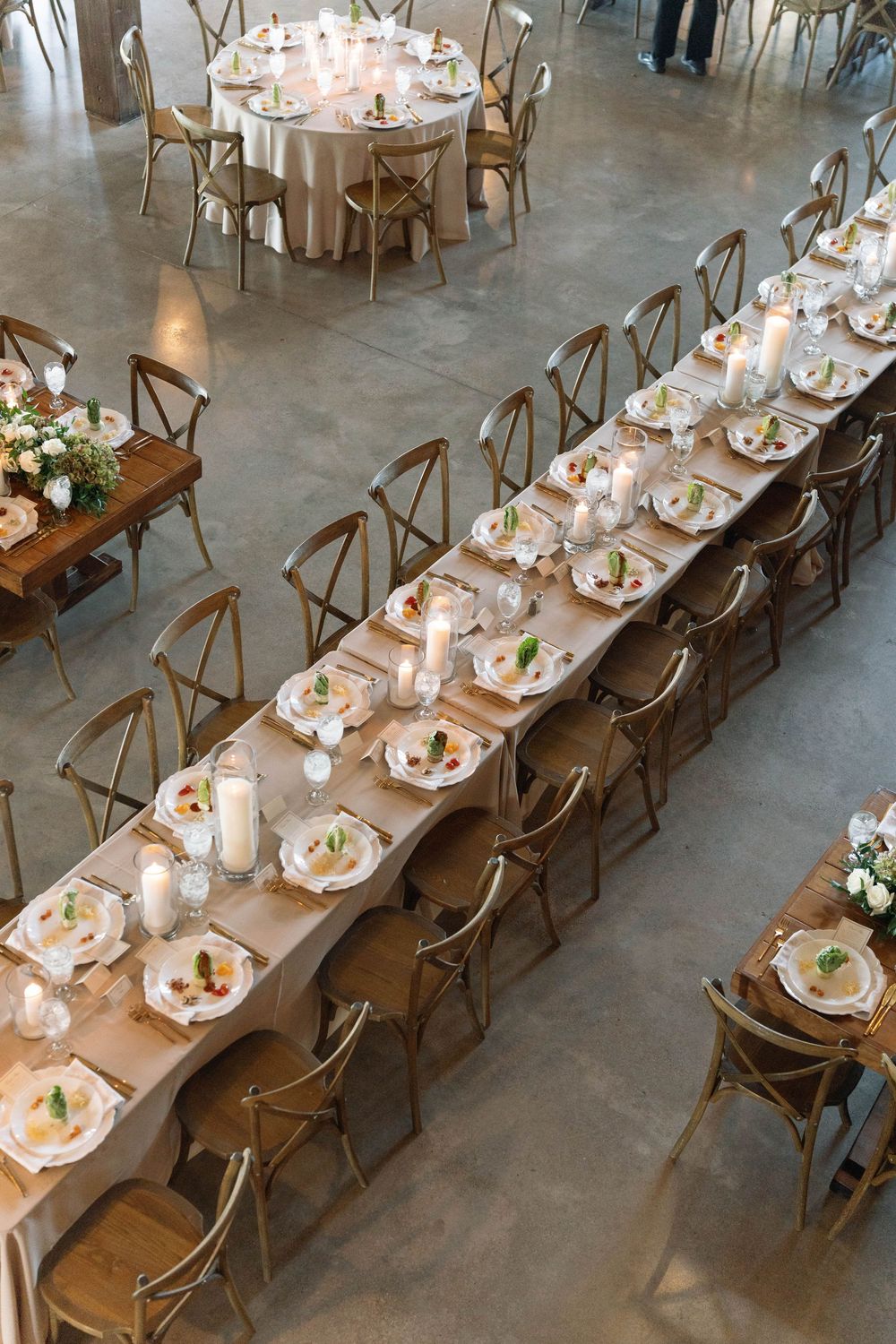 Overhead view of elegant wedding reception with long tables and crossback chairs.