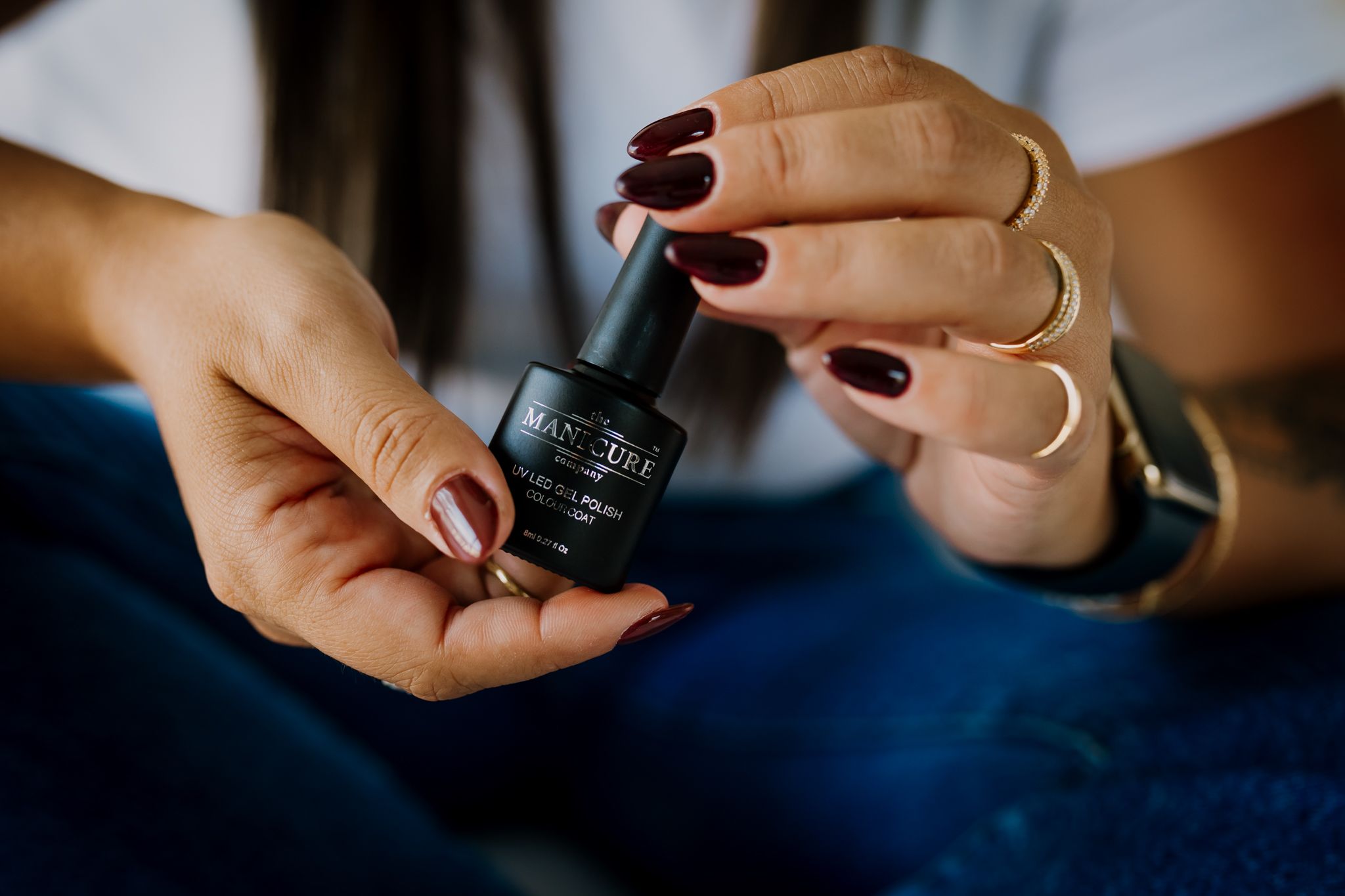 Two hands holds one black nail polish product.