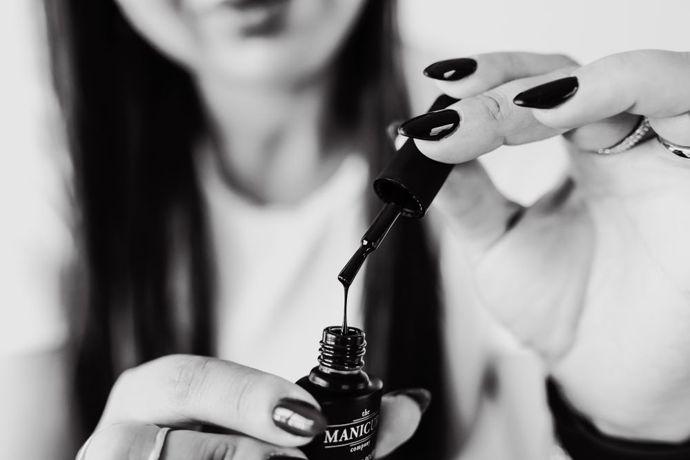Two hands open a nail polish product.