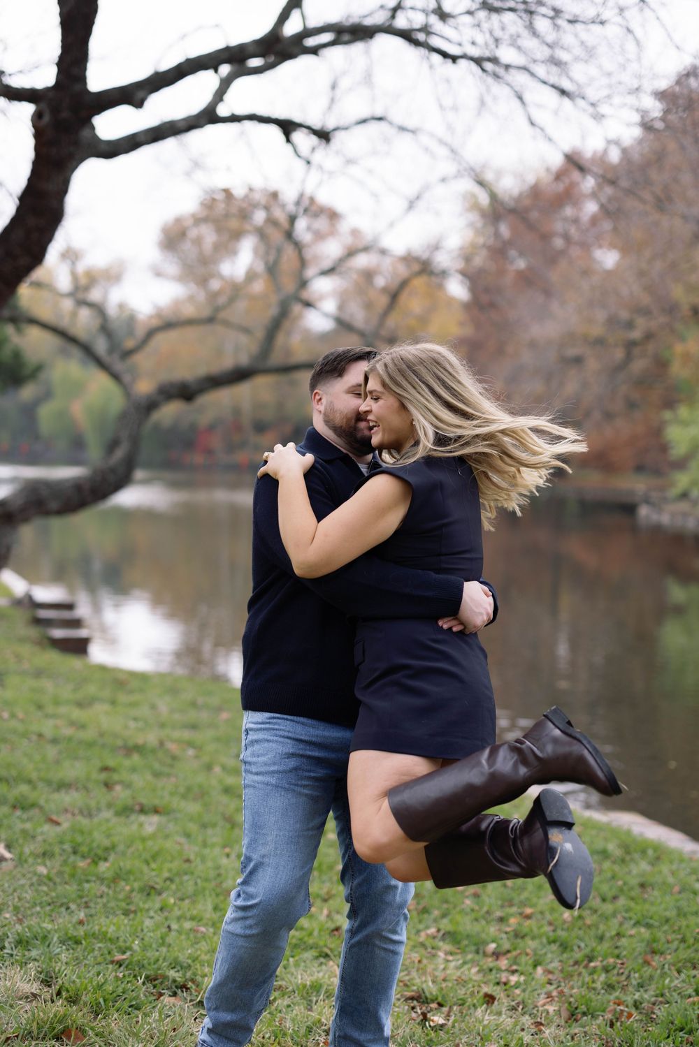 A romantic autumn photoshoot by a lake with fall foliage in the background.