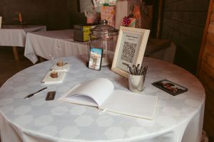 A white tablecloth covered table with an open guest book, pens, and event decor items arranged neatly.