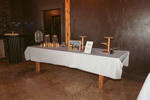 Simple wedding reception display table with guest book and decor items on white tablecloth.