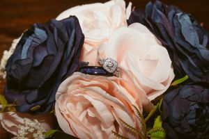Diamond engagement ring nestled among navy blue and blush pink roses.