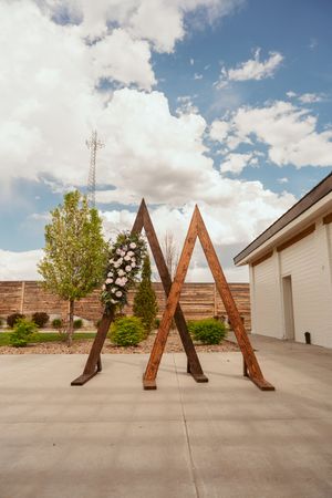 Large wooden letter A sculptures stand in a row against a cloudy sky on a concrete surface.