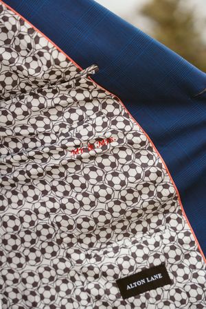 Close-up detail of a fabric pattern featuring repeating soccer ball motifs with a navy blue accent trim.
