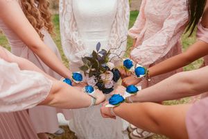 Close-up of coordinated blue bracelets worn by wedding party members holding bouquets.