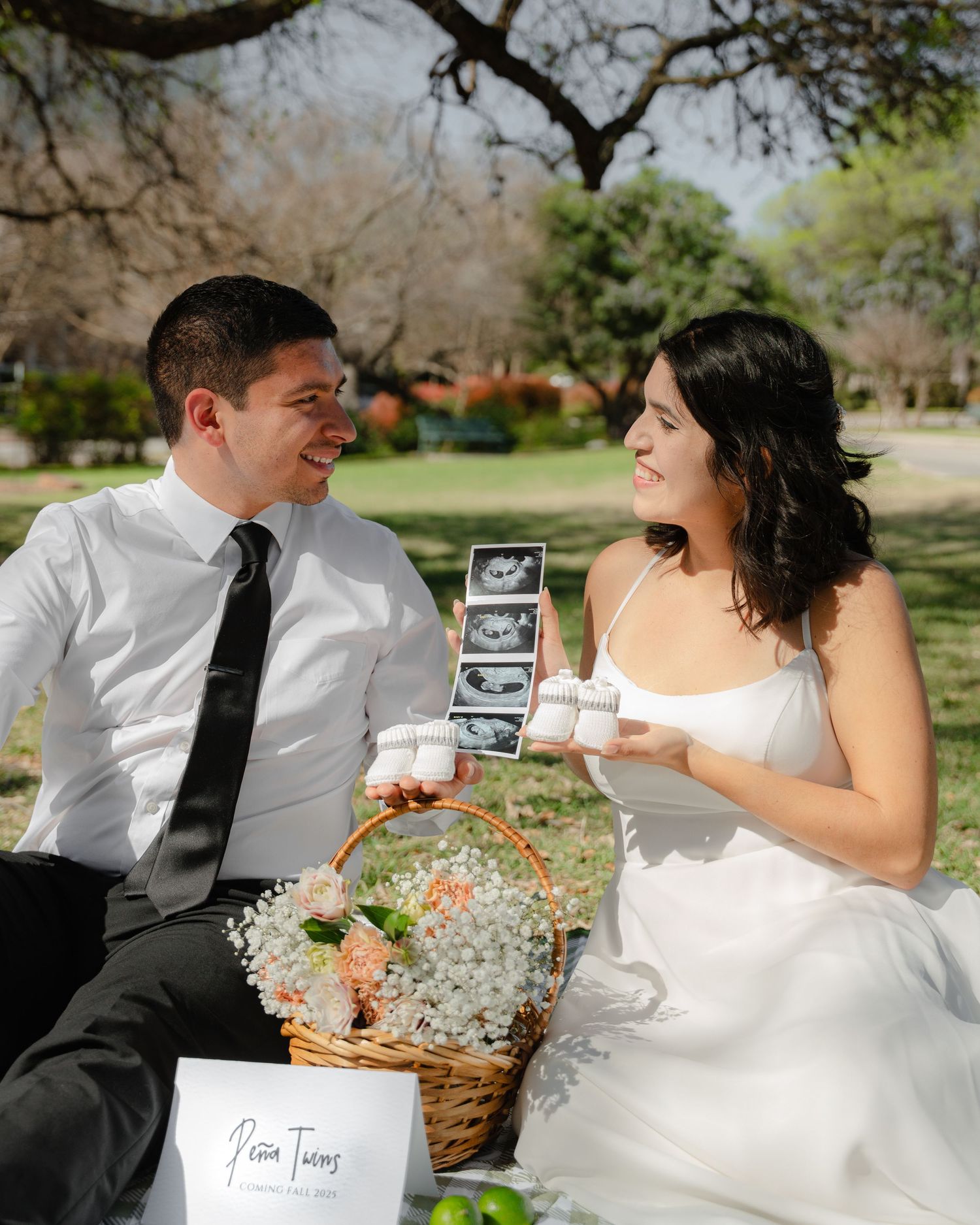 Couple shares special moment during outdoor picnic with pregnancy announcement props.