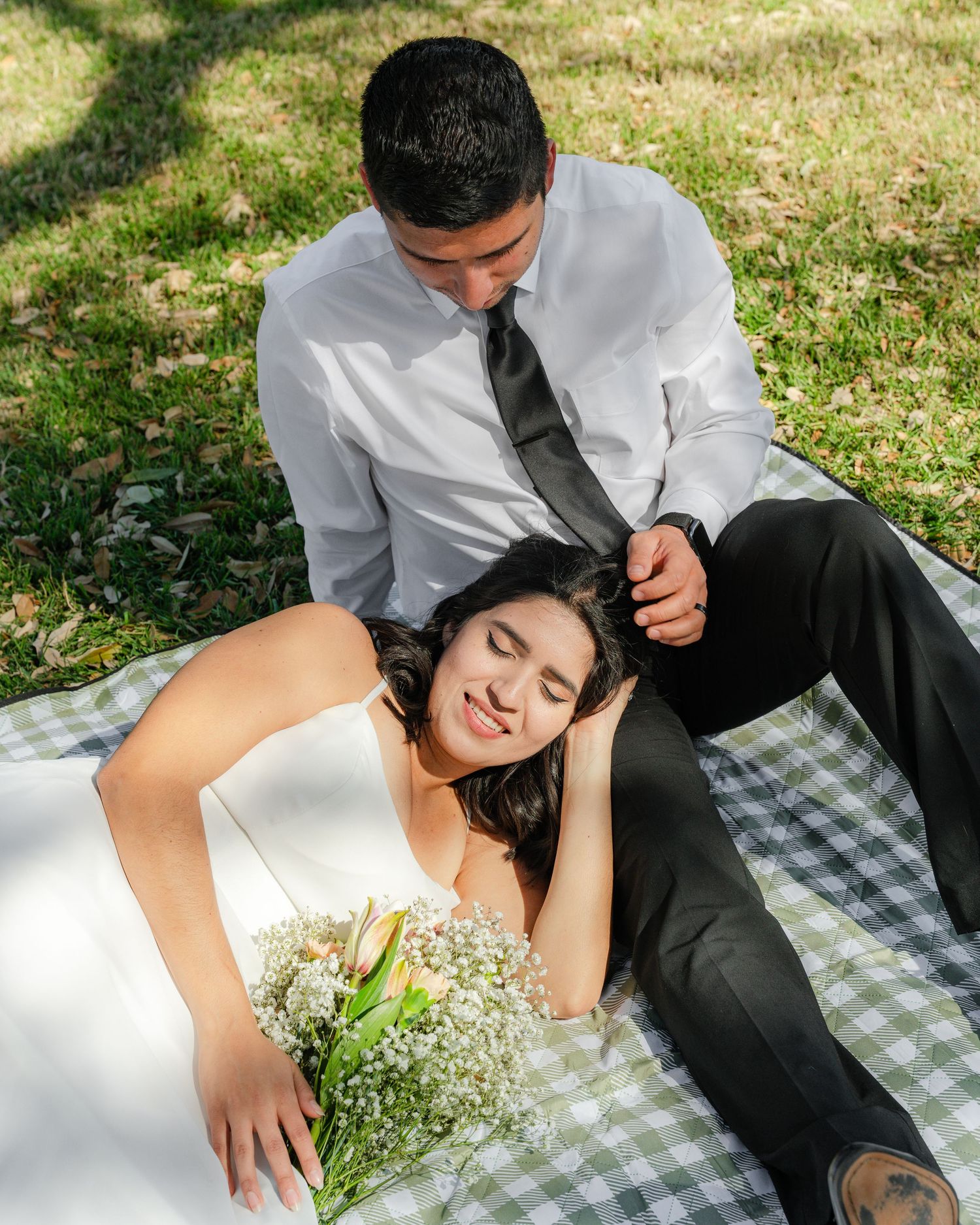 Intimate outdoor picnic scene with couple relaxing on checkered blanket.