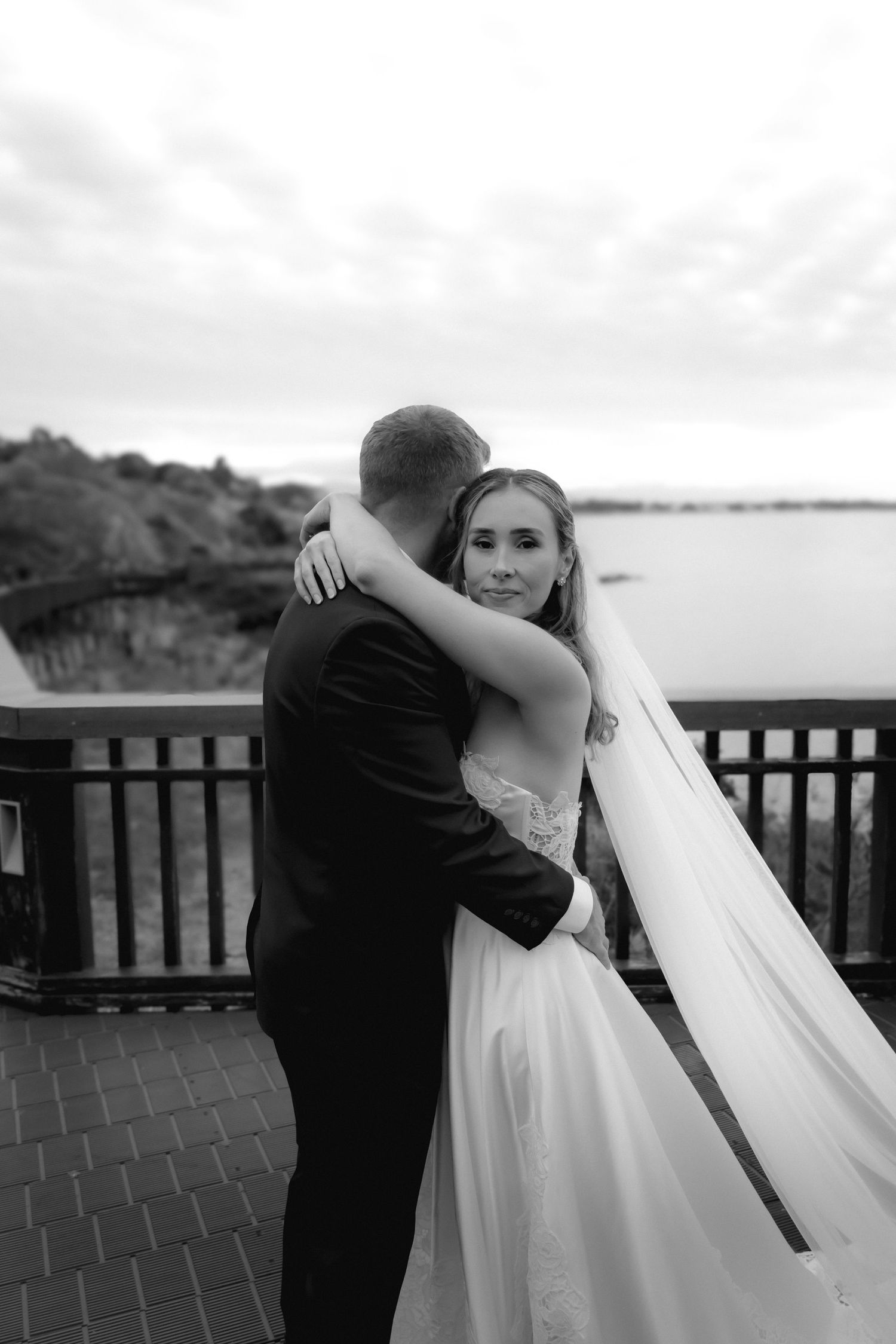 Intimate wedding photos captured on a wooden deck with water views at sunset.