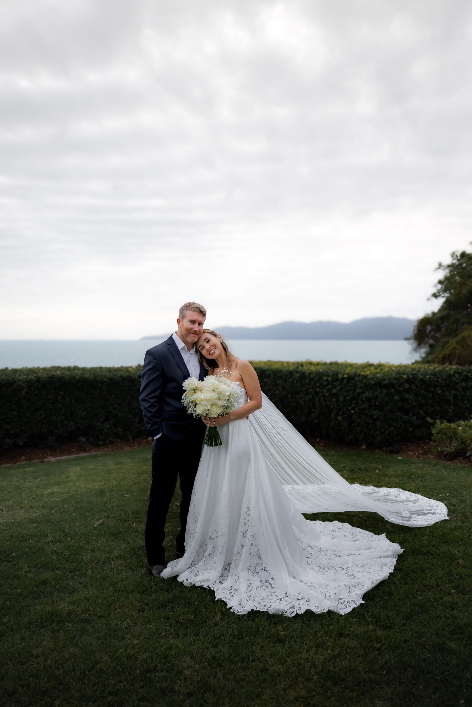 Romantic coastal wedding portraits featuring a flowing white gown and scenic ocean views.