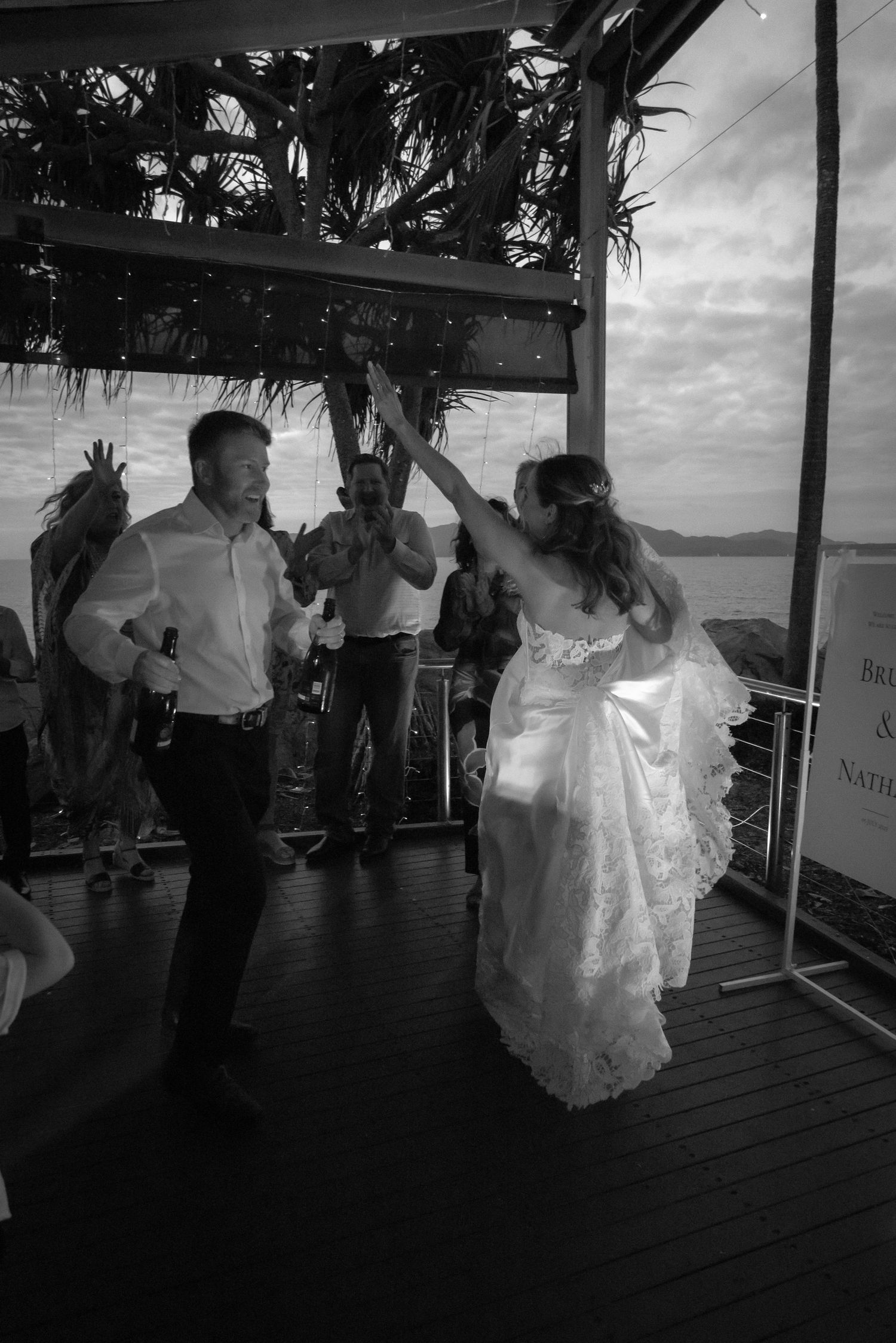 Wedding reception dance party on covered deck overlooking the water at sunset.