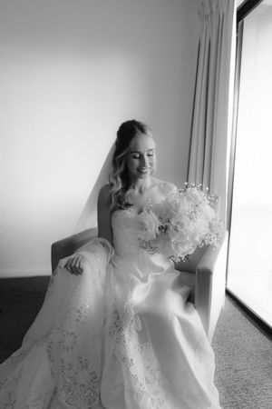 Artistic black and white shots of bride in flowing lace dress near window.