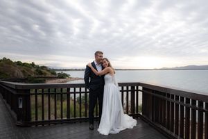 A romantic wedding photo session on a coastal boardwalk at dusk.